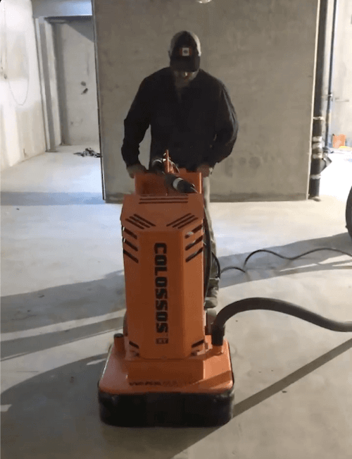 Man grinding concrete garage floor with commercial machine